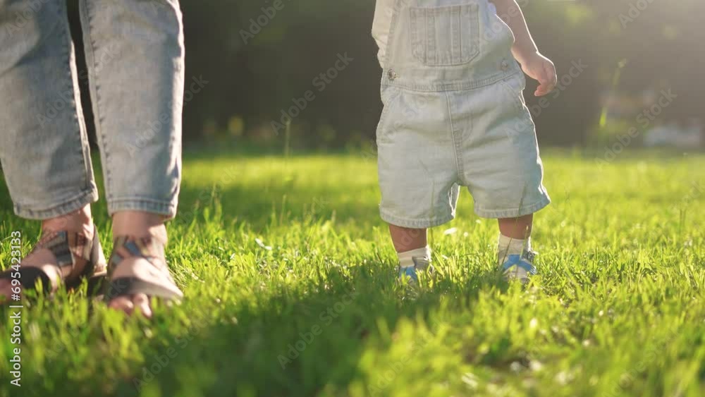 baby first steps. happy family a kid dream concept. baby walks on the grass learns to walk in the city park close-up. baby first steps in lifestyle nature. mom teaches son to walk baby first steps. happy family a kid dream concept. baby walks on the grass learns to walk in the city park close-up. baby first steps in lifestyle nature. mom teaches son to walk