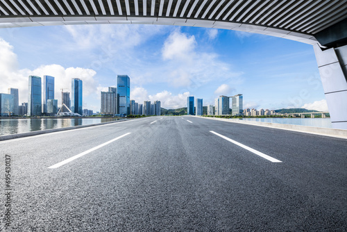 Asphalt road and bridge with city buildings under blue sky