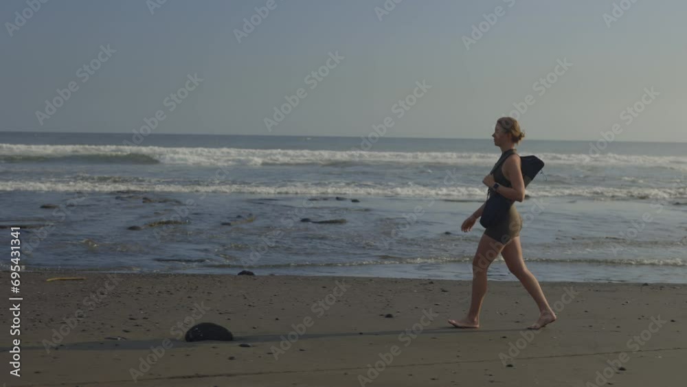 Attractive Sporty Girl Walking on the Beach Barefoot in Yoga Sportswear. Caucasian Female Coach Walking Along the Shore After Class. Beautiful Active Lady on a Walk. Sport and People Concept Attractive Sporty Girl Walking on the Beach Barefoot in Yoga Sportswear. Caucasian Female Coach Walking Along the Shore After Class. Beautiful Active Lady on a Walk. Sport and People Concept