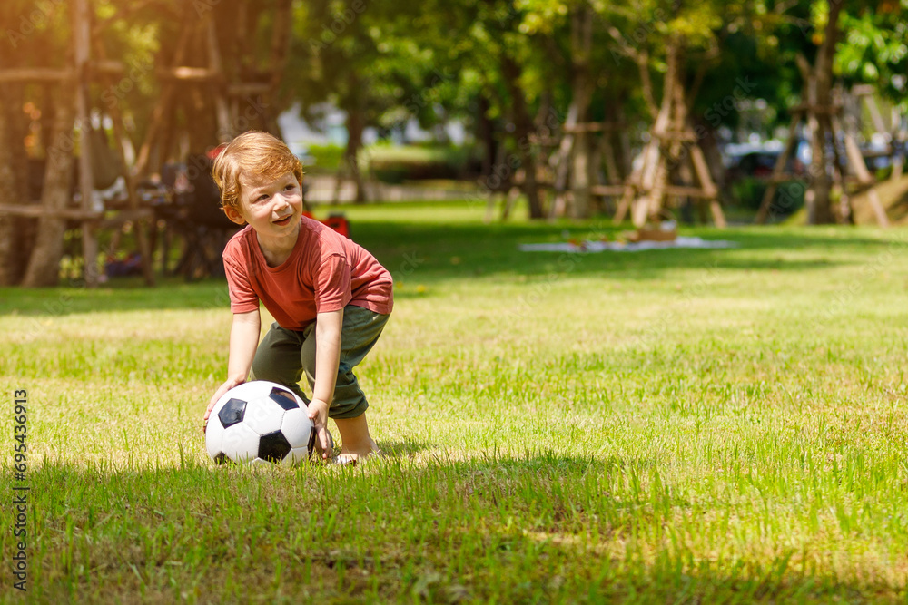 My son enjoys playing football in the backyard. Happy little child in nature in the park