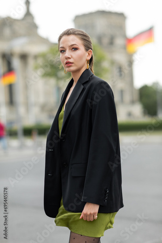 Portrait of young fair haired woman in fashionable silk dress and black jacket on street in Berlin © LIGHTFIELD STUDIOS