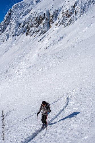 Scialpinista sale lungo un pendio innevato in Canton Ticino, Svizzera