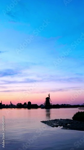 Windmills at famous tourist site Zaanse Schans in Holland on sunset with dramatic sky. Zaandam, Netherlands. Camera pan photo