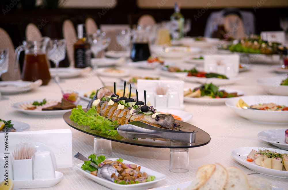 Stuffed fish with olives on a festive table with food, drinks, dishes and utensils