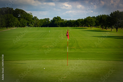 Celebrate the pinnacle of golfing success with this striking stock photo capturing a vibrant "Hole-in-One" flag fluttering proudly against the backdrop of a meticulously maintained green fairway. 