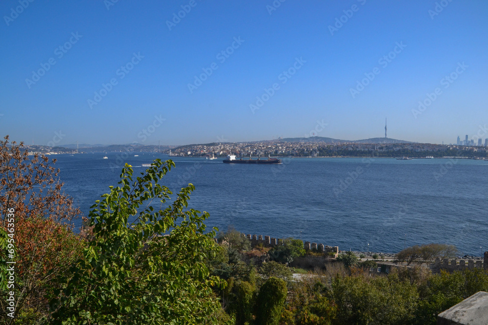 Ship sails past Topkapi Palace on the Bosphorus towards the Sea of Marmara with the Asia side of Turkey in the background.
