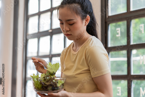 Φωτογραφία Unhappy Asian girl eating green vegetables salad upset bored of dieting