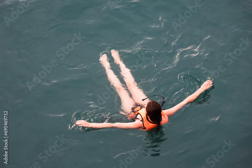 Billede på lærred Girl in life vest swimming in sea water, top view