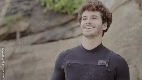 Jovem sorridente vestindo seu traje de surf. Cinematico 4k. photo