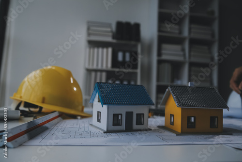 architectural model of houses on desk with drawing technical tools and blueprint rolls, isolated on white background, for building construction plan, interior designer and architect work concept