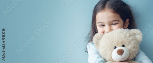 Smiling Young Girl with Teddy Bear on Blue Background