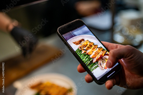 hand with smartphone photographing food at restaurant or cafe photo