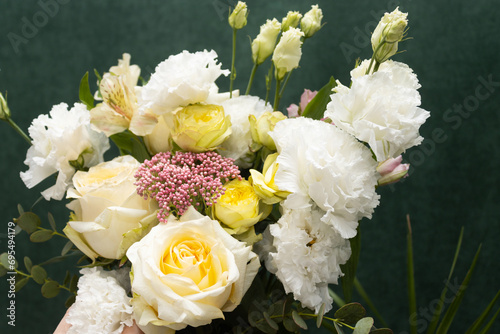 Floristry. Flowers. A florist girl collects a bouquet of white and yellow roses. Blurred background.