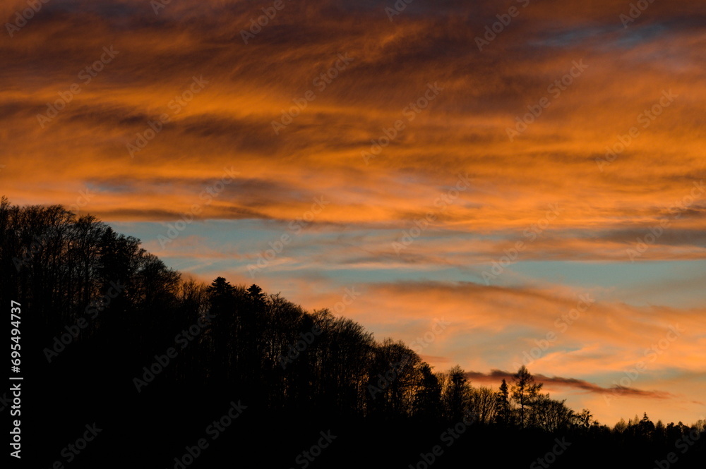 Forest on the hill and sunset on the background. Landscape of Czech republic nature. Dramatic colorful sky.