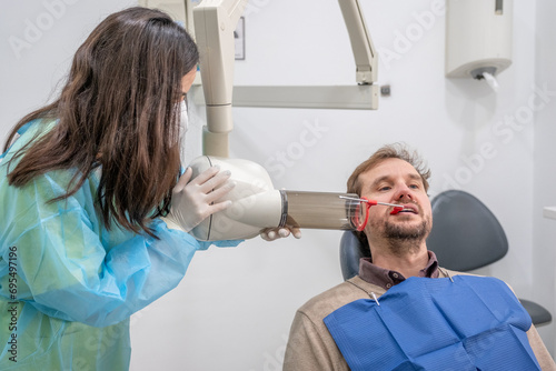 A dental assistant taking an X-ray of a patient's mouth.
