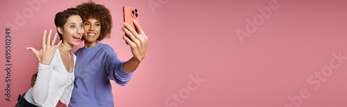 happy lesbian woman showing engagement ring on her finger while taking selfie with fiancee, banner photo