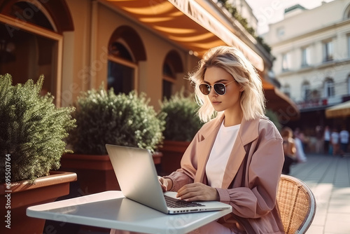 Fashion woman in working remote on laptop in public place at daytime.