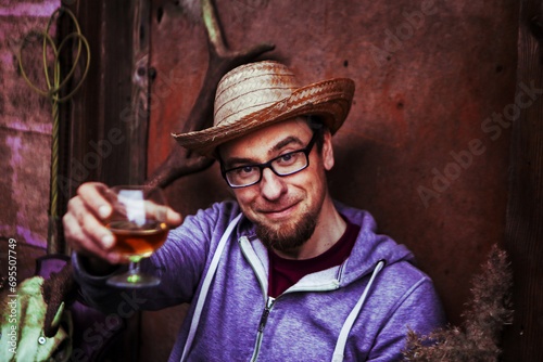 Portrait of handsome man in straw hat with alcohol glass