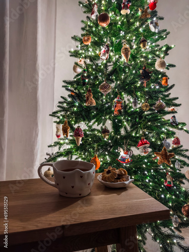A cozy evening - a cup of tea, cookies on a wooden table against the background of a Christmas tree
