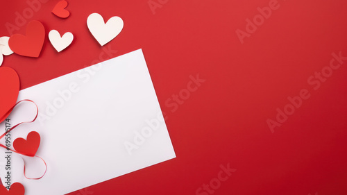 Flat lay with white blank postcard lies on red table and hearts made of paper and a garland around