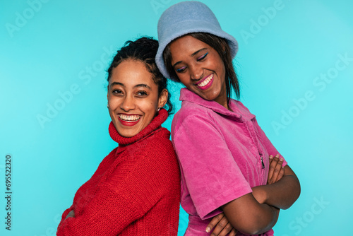 Two women in vivid tops share a close and affectionate embrace, smiling warmly photo
