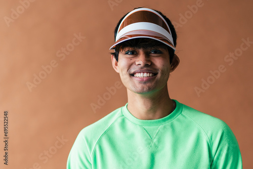 Man in green sweater with visor cap smiling widely, teeth showing photo