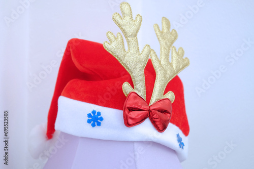 Christmas hat decorated by golden deer antler and red ribbon