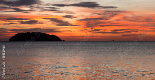 Dramatic Sunset Over Water with Island on Horizon