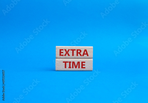 Extra time symbol. Concept word Extra time on wooden blocks. Beautiful blue background. Business and Extra time concept. Copy space