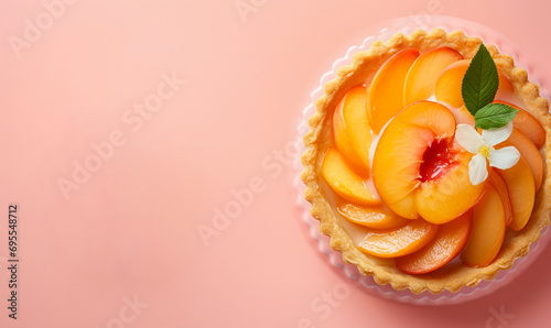 fresh peach tart on pastel pink background with whole peach and flower with copy space 