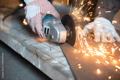 Man is cutting a metal sheet by angle grinder saw. photo