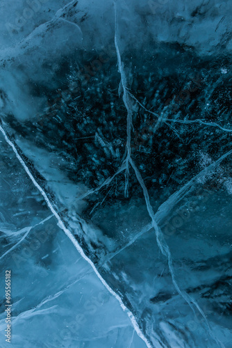 Top vies of a texture cracks transparent ice on a Baikal lake on a snowy winter day. Natural background 