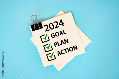 Text 2024 GOAL PLAN ACTION on sticky notes with copy space and paper clip isolated on red background. Finance and economics concept.