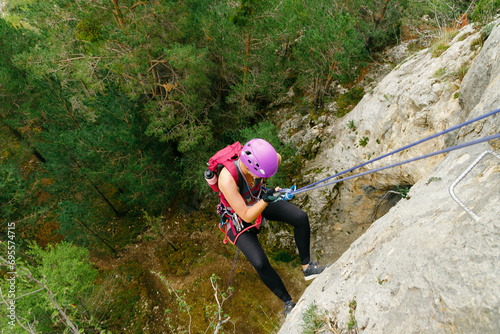 Woman initiating rappel with a forest background photo