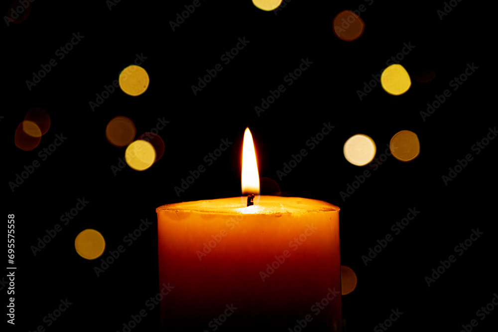 Candle burns Isolated On Black background with Christmas Lights Defocused Bokeh. Candle burns Isolated On Black background with Christmas Lights Defocused Bokeh.