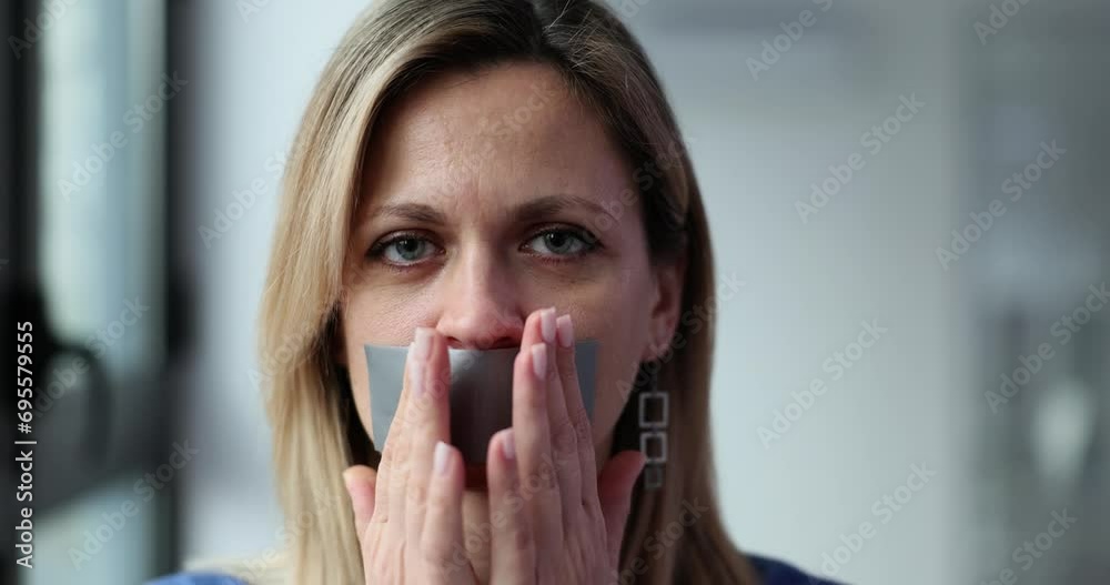 Young woman with lips taped over mouth Young woman with lips taped over mouth