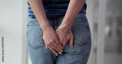Woman holding butt and suffering from pain closeup photo