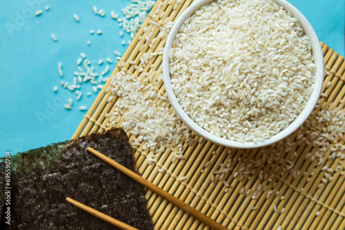 Dry white rice in a bowl and chinese chopsticks. Flat lay, top view, copy space