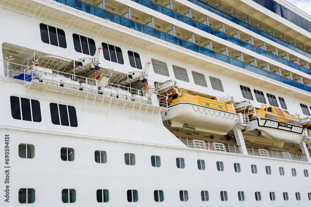 Naklejka premium Side view of cruise ship with hanging lifeboats and liferafts, emergency rescue boats and rafts