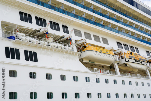 Side view of cruise ship with hanging lifeboats and liferafts, emergency rescue boats and rafts photo