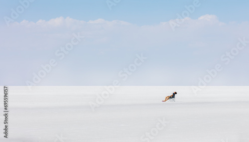 A woman is resting, sunbathing on a salt lake. Salar de Uyuni. Bolivia. Panorama .Minimalism