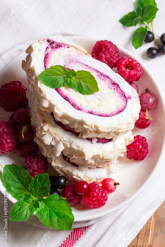 Obraz na płótnie Meringue roll with whipped cream and currant curd, served with berries on a ceramic plate. Rustic style. w salonie