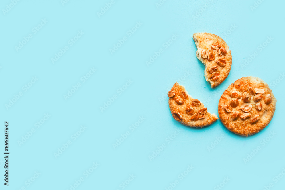 Tasty round cookies with nuts on blue background, top view, copy space