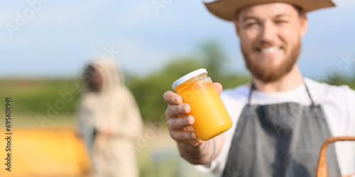 Beekeeper with jar of honey at apiary. Banner for design