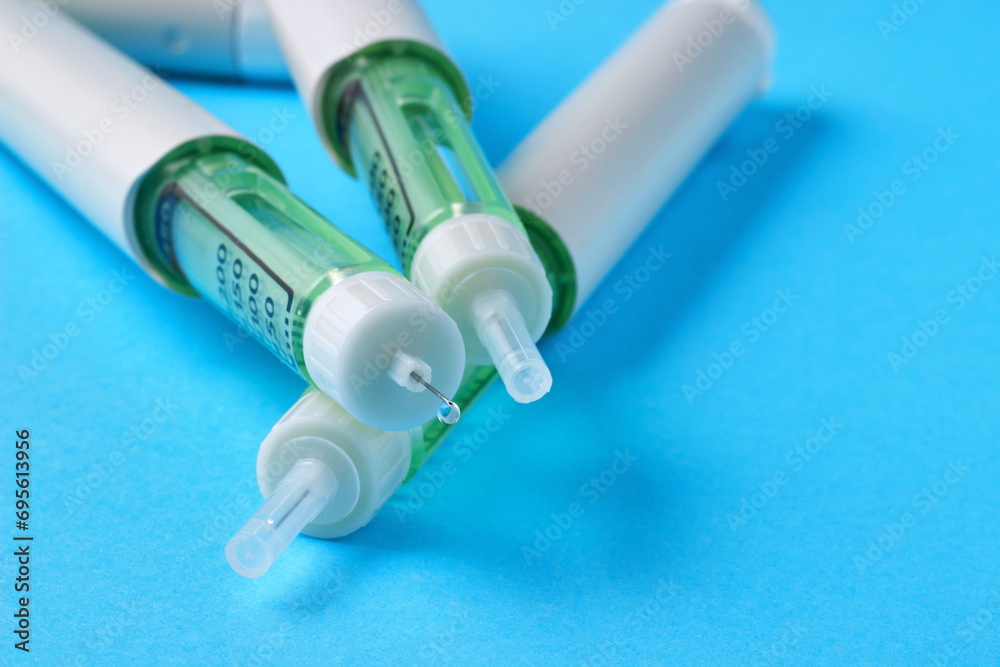 Insulin syringe pen with a drop of medicine at the end of the needle on a blue background Insulin syringe pen with a drop of medicine at the end of the needle on a blue background
