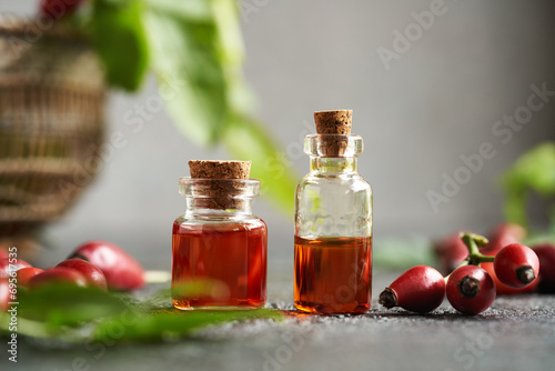 Fototapeta Naklejka Na Ścianę i Meble -  Two bottles of rose hip seed oil with fresh rosehips on a table