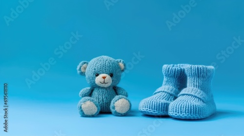 Knitted baby blue booties and toy bear on a blue background  photo