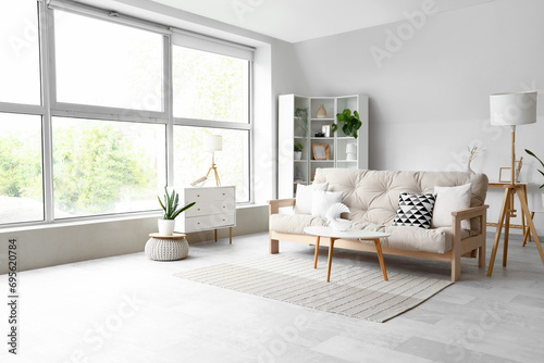 Interior of light living room with cozy sofa and white furniture photo
