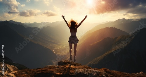free pictures of person jumping into air on a mountain with sun behind her photo