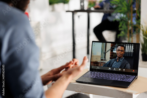 Entrepreneur collaborating with team leader on project in virtual workspace through video call. Employee presenting business plan to company ceo in online meeting on portable computer